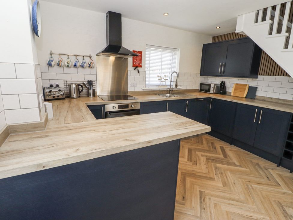 A kitchen with cabinets and appliances at Seahorse Cottage in Chathill