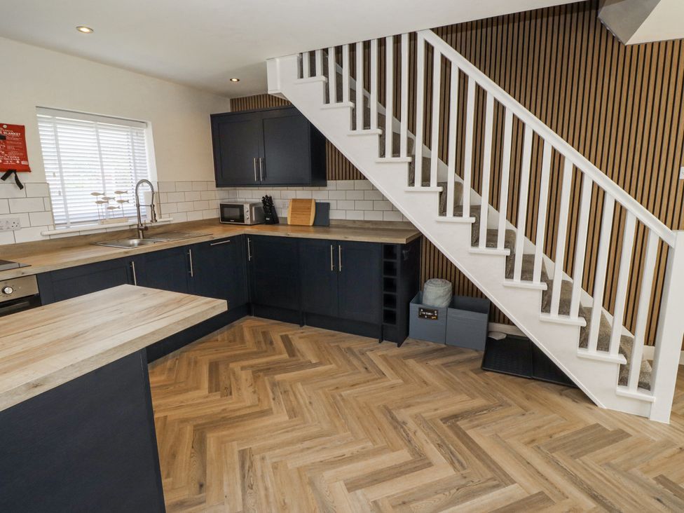 A kitchen with a sink and countertop near stairs at Seahorse Cottage in Chathill