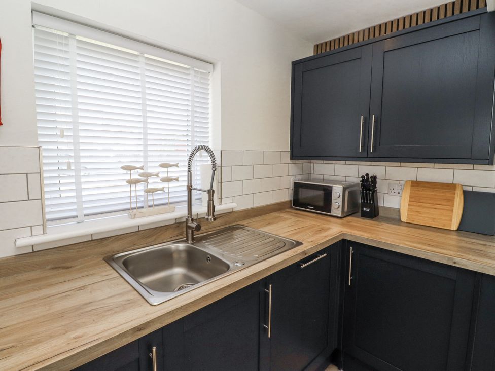 A kitchen with a sink and microwave at Seahorse Cottage in Chathill