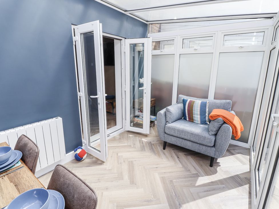 A conservatory with a chair and dining table at Seahorse Cottage in Chathill