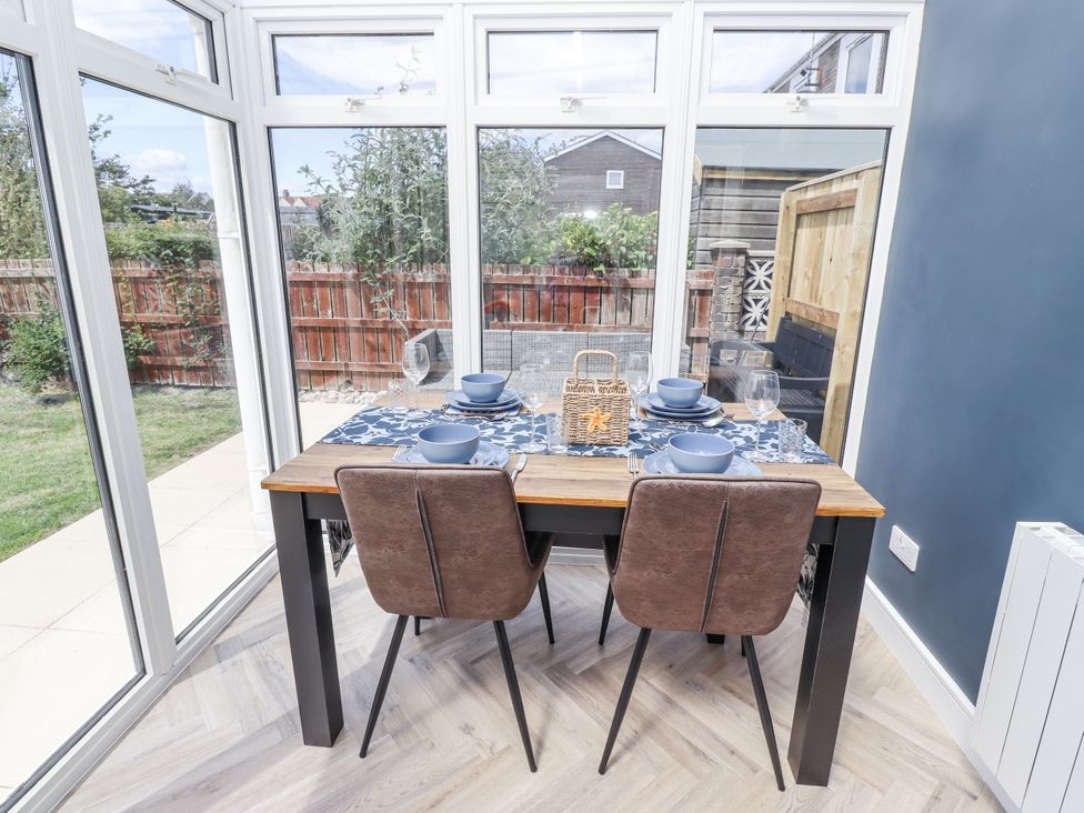 A conservatory with a dining table and chairs at Seahorse Cottage in Chathill