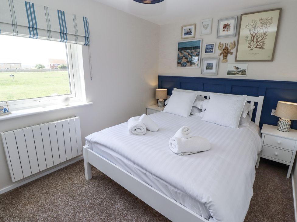A bedroom with a double bed and wall art at Seahorse Cottage in Chathill