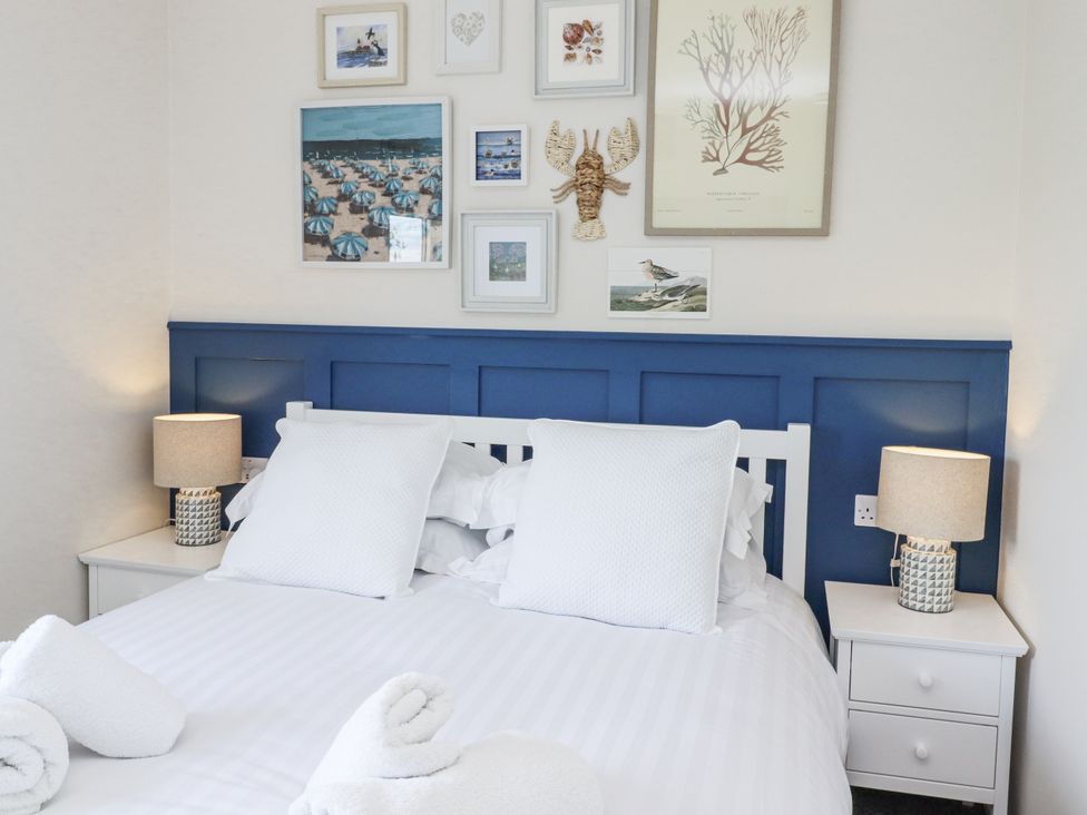A bedroom with a double bed and wall art at Seahorse Cottage in Chathill