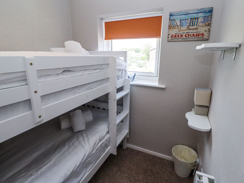 A bedroom with a bunk bed and a window at Seahorse Cottage in Chathill