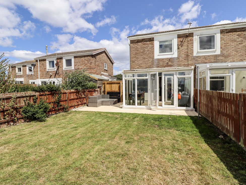 A garden with a house and patio area at Seahorse Cottage in Chathill