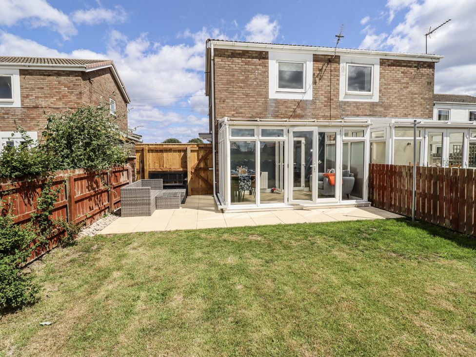 A garden with a house and patio at Seahorse Cottage in Chathill