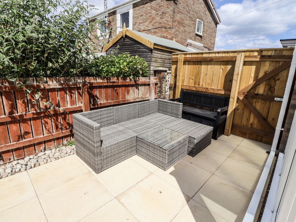 A garden with outdoor furniture and a wooden fence at Seahorse Cottage in Chathill