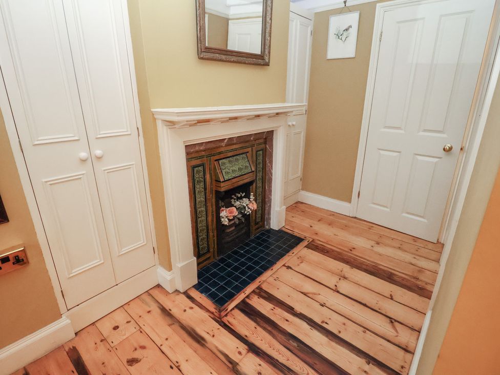 A hallway with a fireplace and wooden flooring at The Anchorage