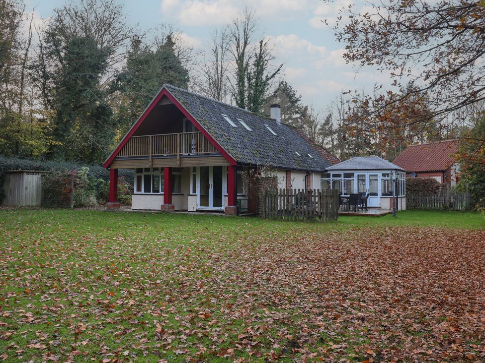 A house with a balcony and conservatory in a green garden at The Anchorage