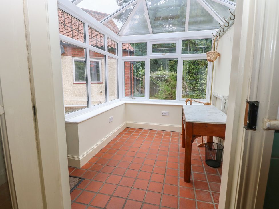 A conservatory with a table and windows at The Anchorage in Hoveton & Wroxham
