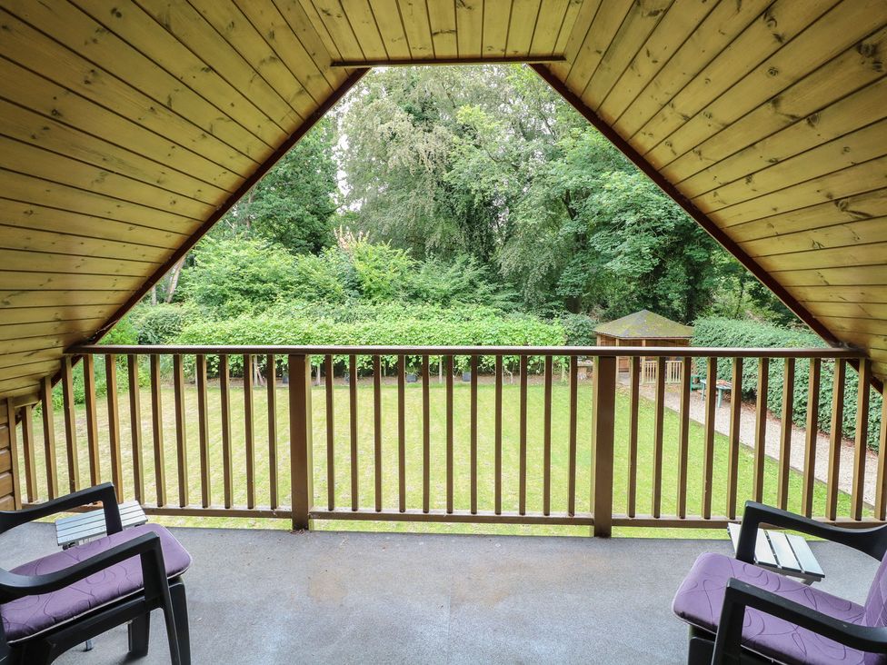 A balcony with chairs and table overlooking a garden at The Anchorage in Hoveton & Wroxham