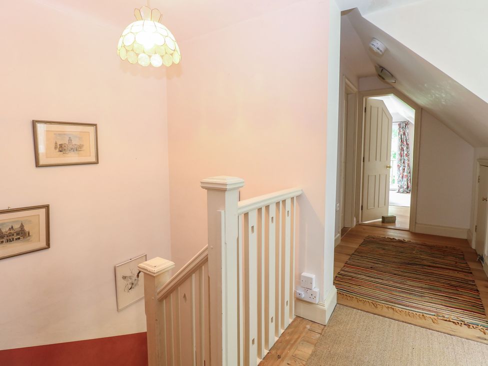 A hallway with stairs and paintings at The Anchorage in Hoveton & Wroxham