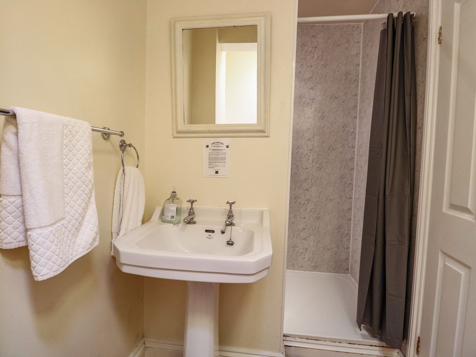 A bathroom with a sink, mirror, and shower at The Anchorage in Hoveton & Wroxham