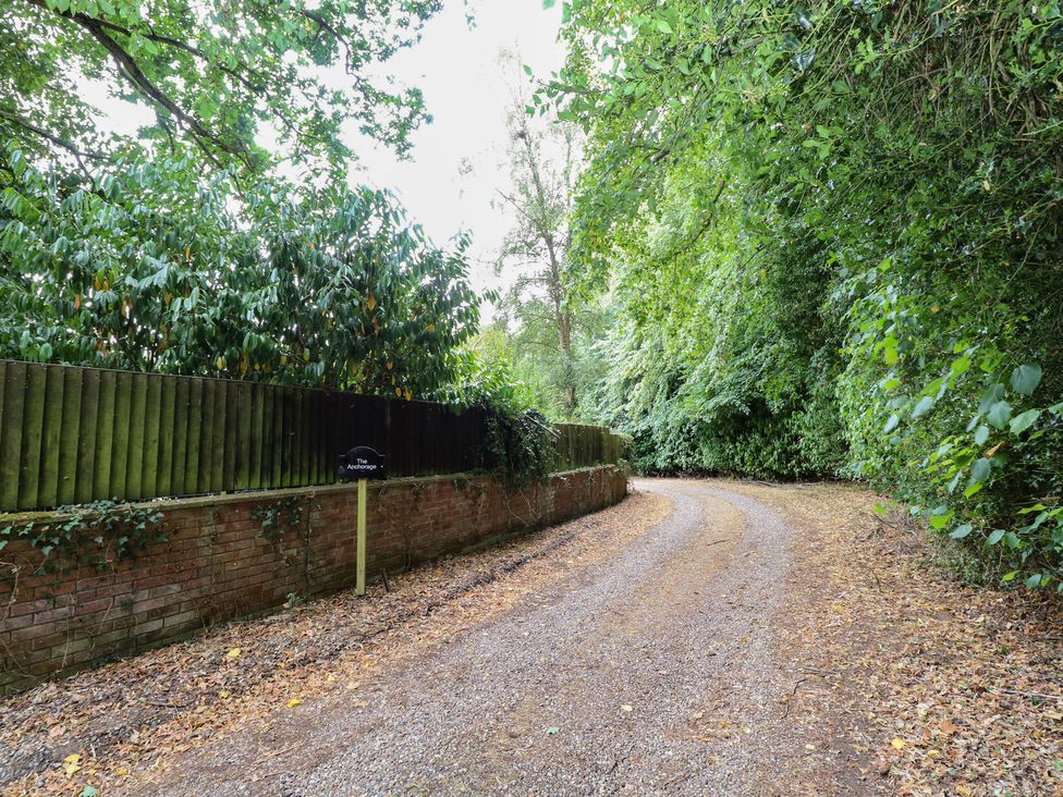 A gravel path with a fence and trees at The Anchorage in Hoveton & Wroxham