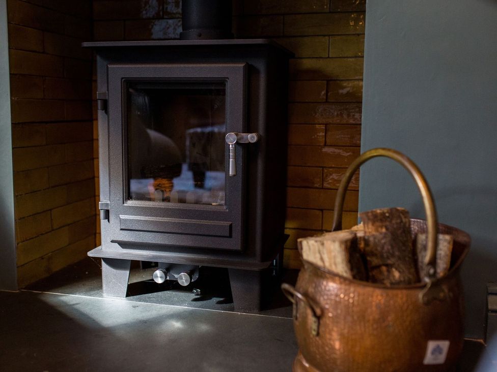 A wood stove and a basket of firewood at Grove House in Grange-Over-Sands