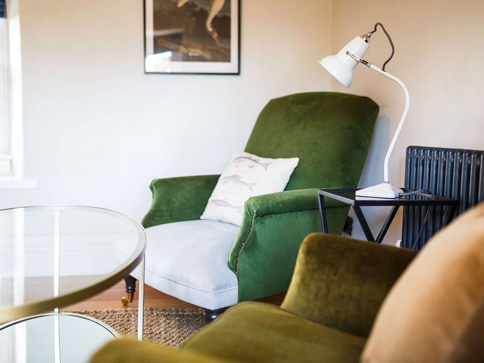 A living room with an armchair and lamp at Grove House in Grange-Over-Sands