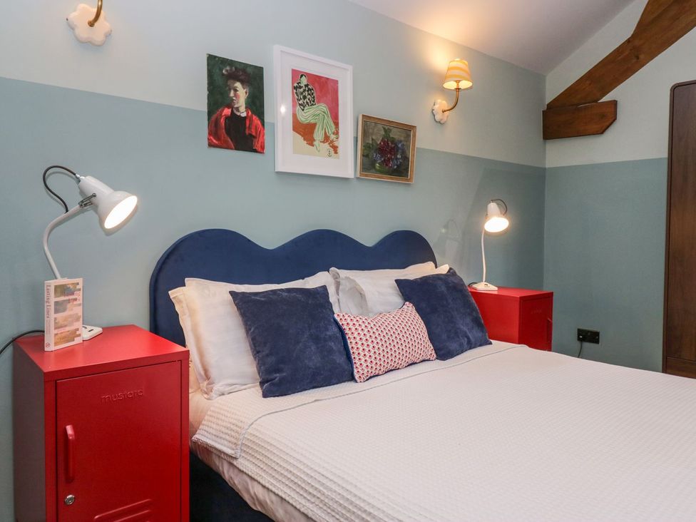 A bedroom with a blue bed and red nightstands at Grove House Grange-Over-Sands