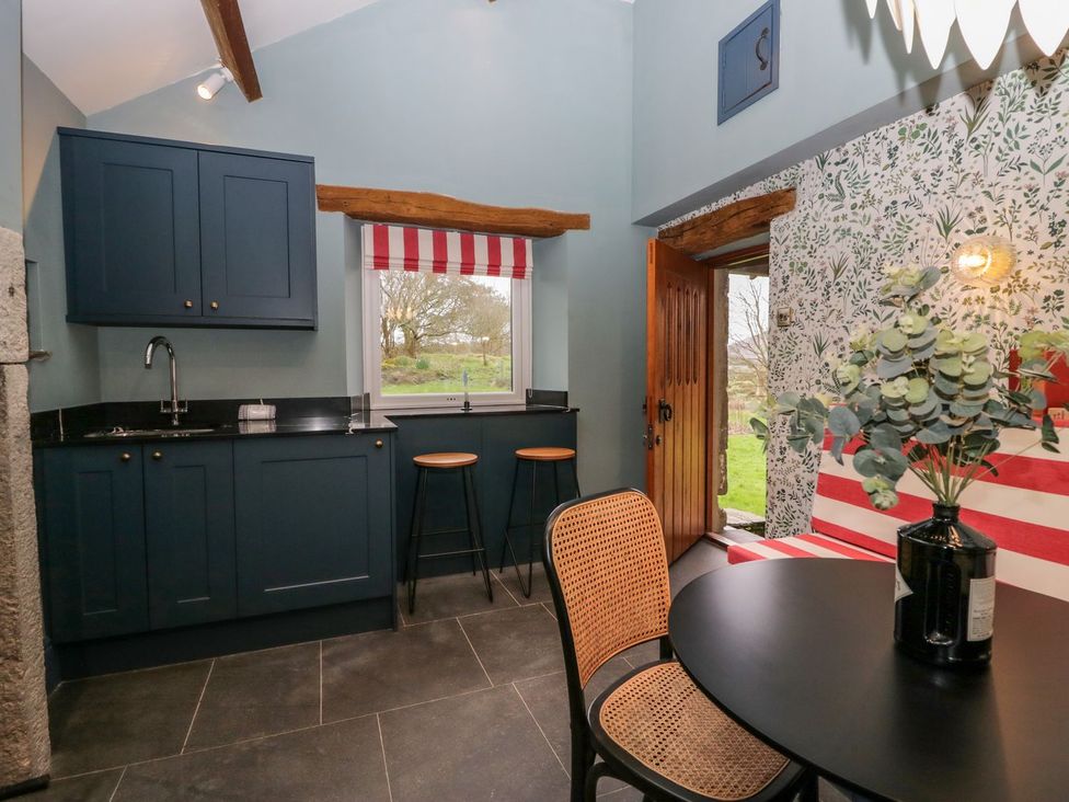 A kitchen with a sink and bar stools at Grove House in Grange-Over-Sands