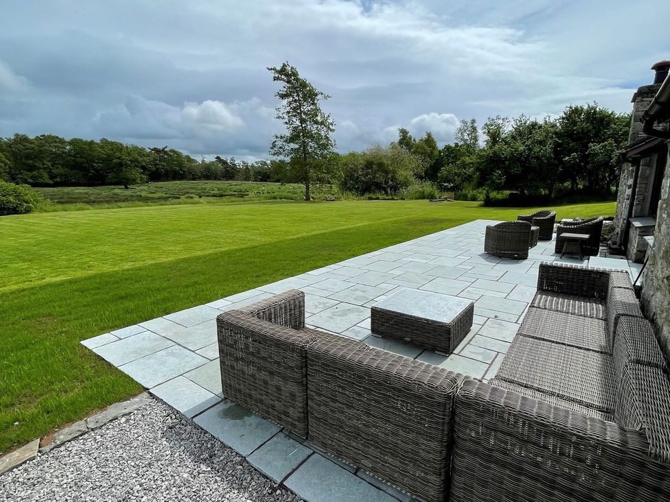 A patio with outdoor furniture and a grassy area at Grove House in Grange-Over-Sands