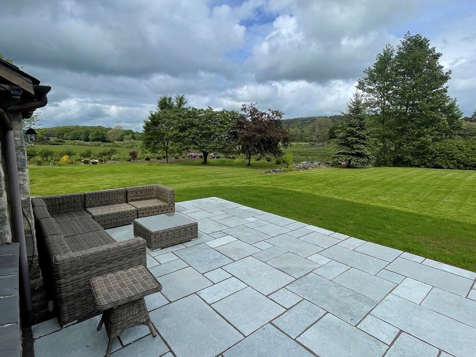 A garden with a patio and sectional sofa at Grove House in Grange-Over-Sands