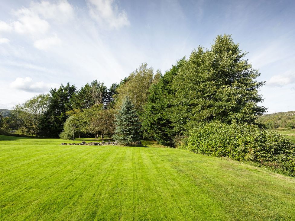 A garden with trees and a stone arrangement at Grove House in Grange-Over-Sands