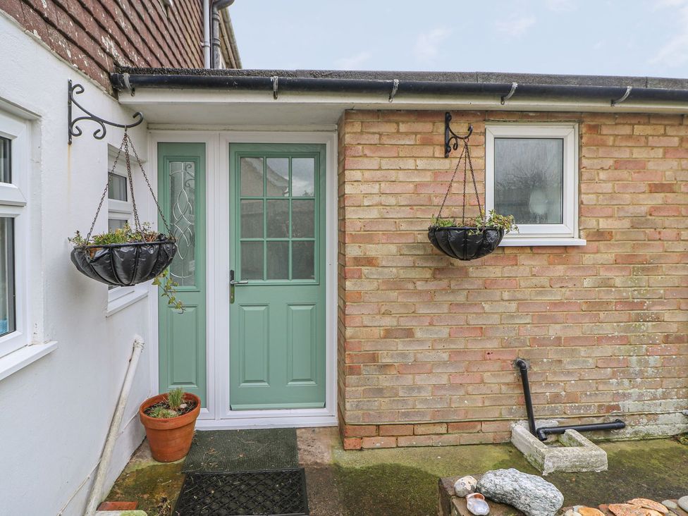 An entrance area with a green door and hanging planters at 3 Seaview Cottages Normans Bay near Bexhill-on-Sea