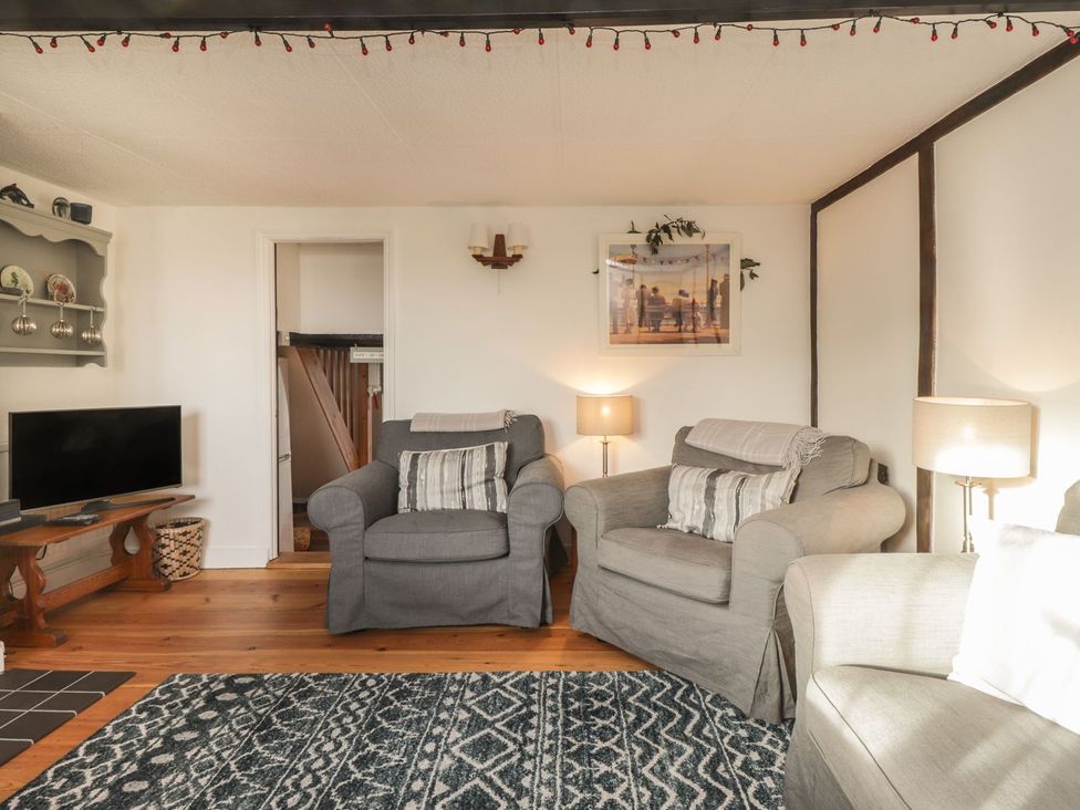 A living room with armchairs and a television at 3 Seaview Cottages in Normans Bay near Bexhill-on-Sea