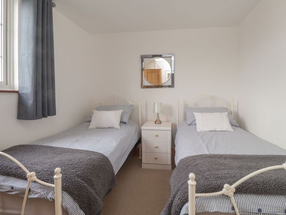 A bedroom with two single beds and a nightstand at 3 Seaview Cottages Normans Bay near Bexhill-on-Sea