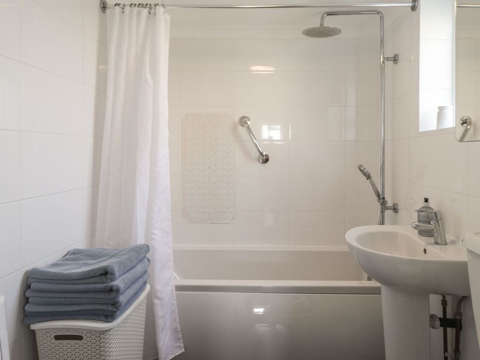 A bathroom with a bathtub, sink, and towels at 3 Seaview Cottages Normans Bay near Bexhill-on-Sea