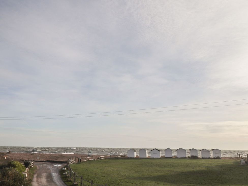 A beach view with beach huts near the ocean at 3 Seaview Cottages in Normans Bay near Bexhill-on-Sea