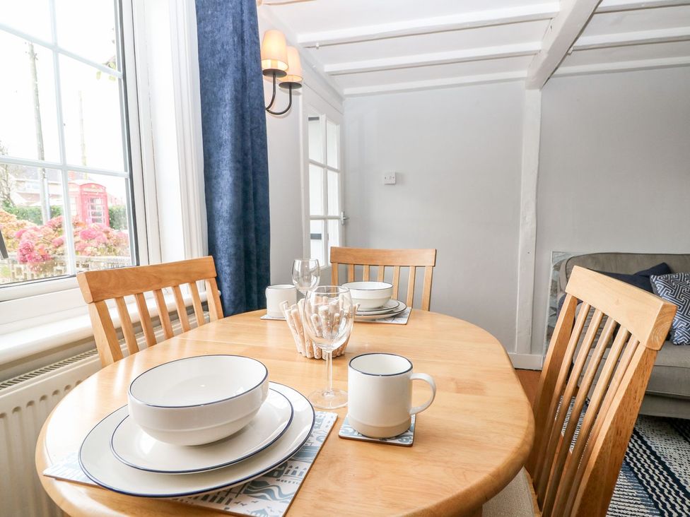A dining room with a wooden table set for dinner at 2 Seaview Cottages Normans Bay near Bexhill-On-Sea
