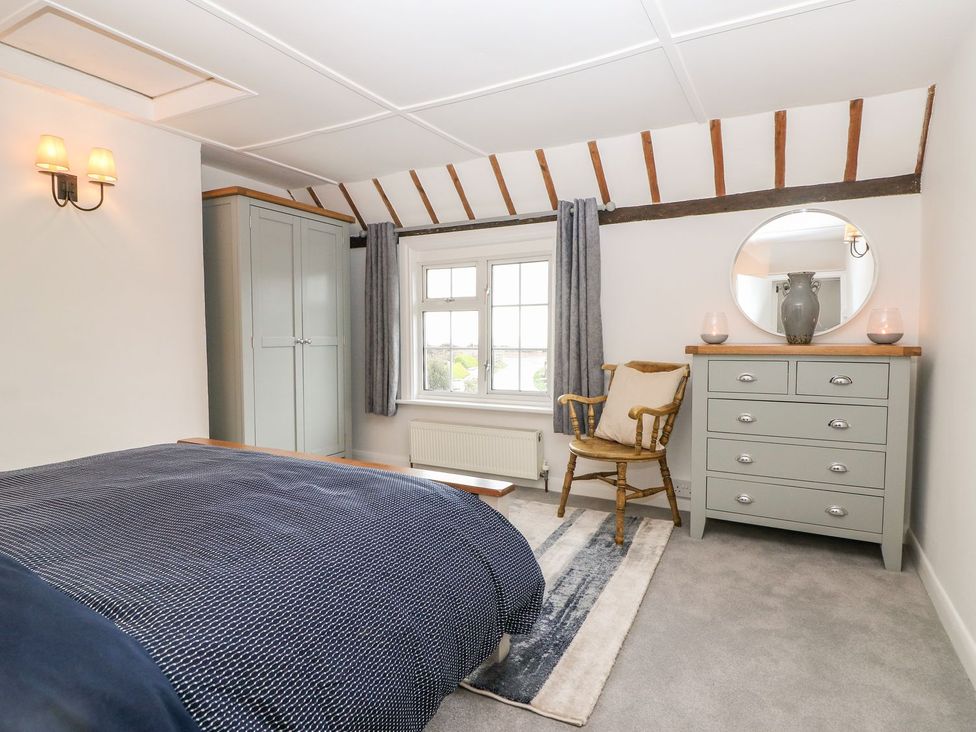 A bedroom with a bed and wardrobe at 2 Seaview Cottages Normans Bay near Bexhill-On-Sea