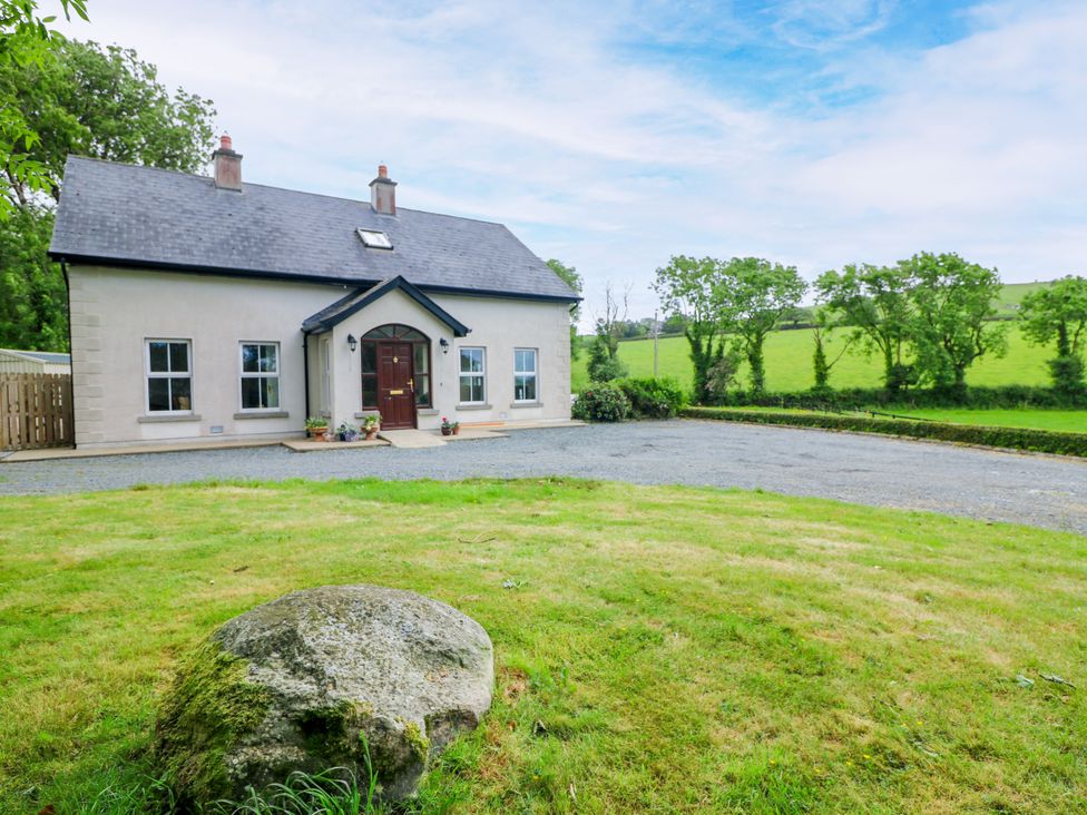 A house with a front door and windows surrounded by grass and trees at The Lodge in Gorey, County Wexford