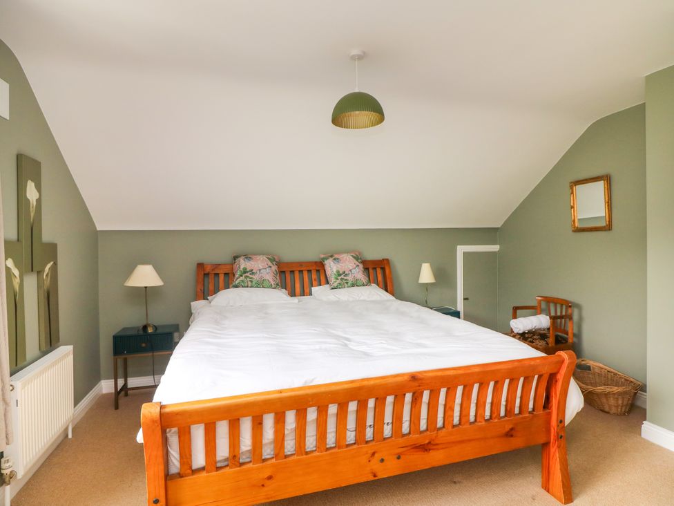 A bedroom with a bed, lamp, nightstand and mirror at The Lodge in Gorey, County Wexford