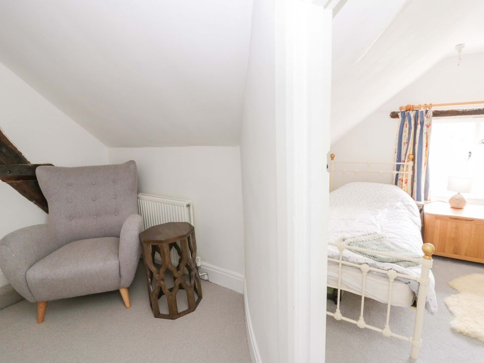 A bedroom with a bed and an armchair at The Old Shop in Builth Wells