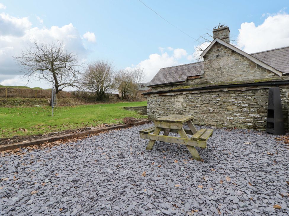 An outdoor area with a picnic table and stone wall at The Old Shop in Builth Wells
