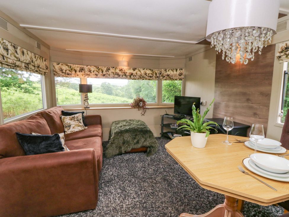 A living room with a sofa, TV, and dining table at Gwybedog in Llanwrda