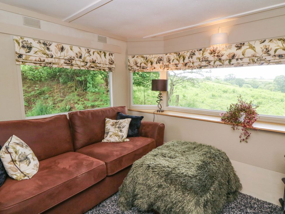 A living room with a sofa and lamp at Gwybedog in Llanwrda