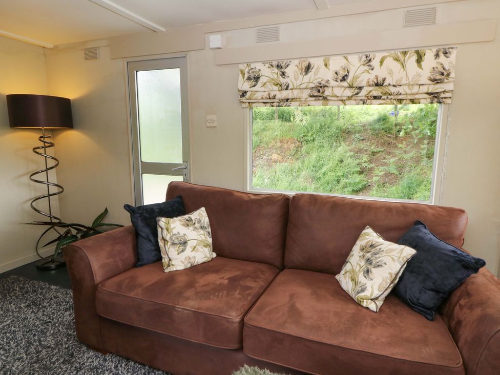 A living room with a couch and lamp at Gwybedog Llanwrda