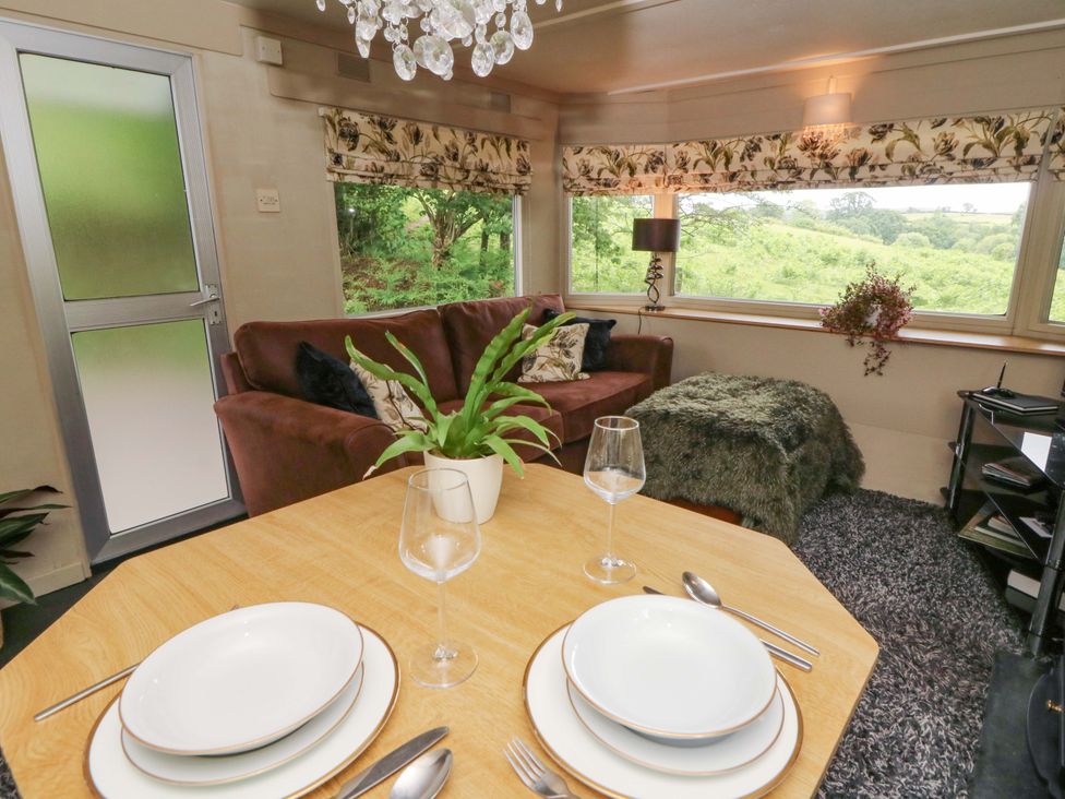 A living room with a sofa and dining table at Gwybedog in Llanwrda
