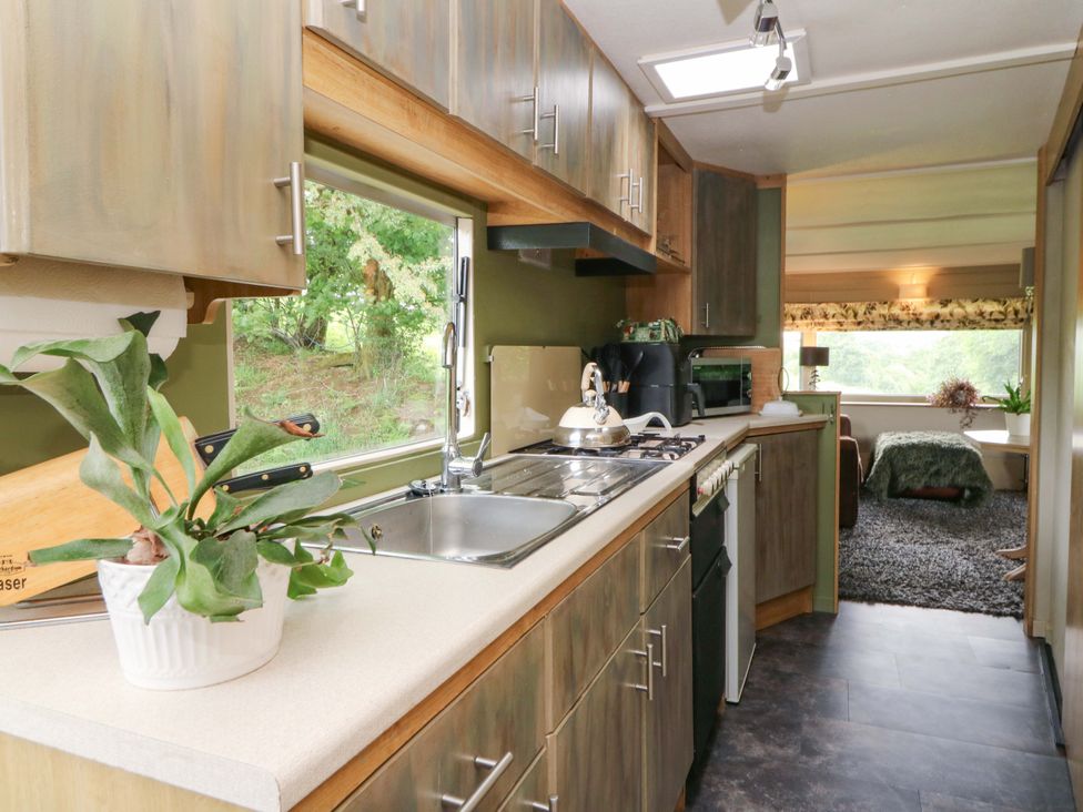A kitchen featuring a sink, stove and cabinets at Gwybedog in Llanwrda