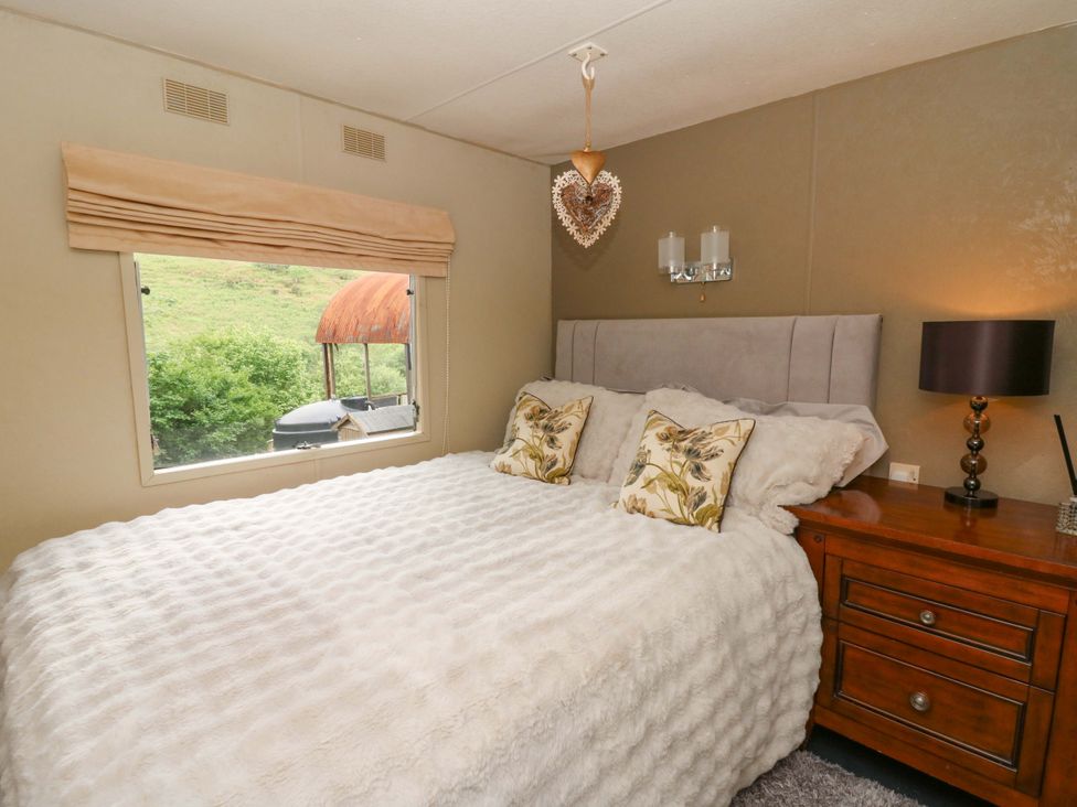 A bedroom with a bed, pillows, and a window at Gwybedog in Llanwrda