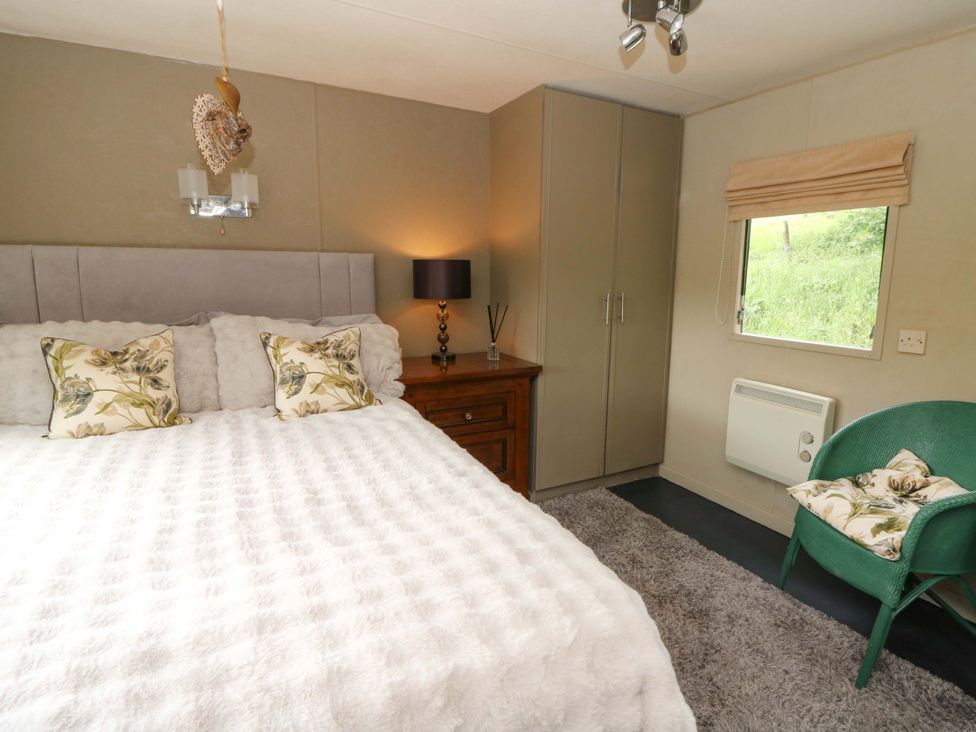 A bedroom with a bed and a wardrobe at Gwybedog in Llanwrda