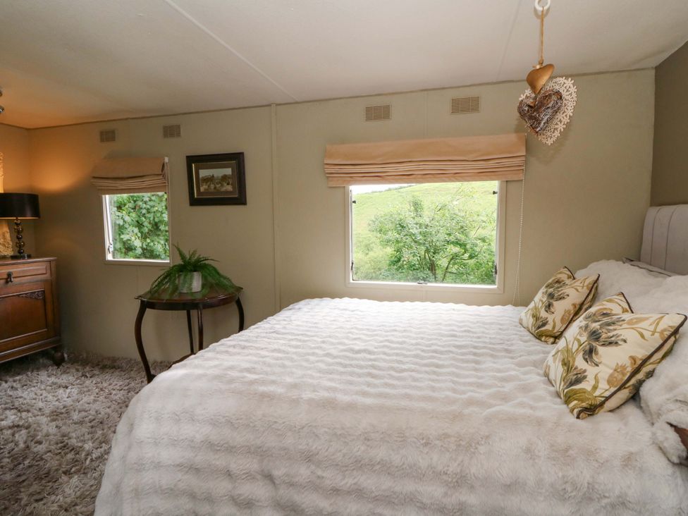 A bedroom with a bed and windows at Gwybedog in Llanwrda