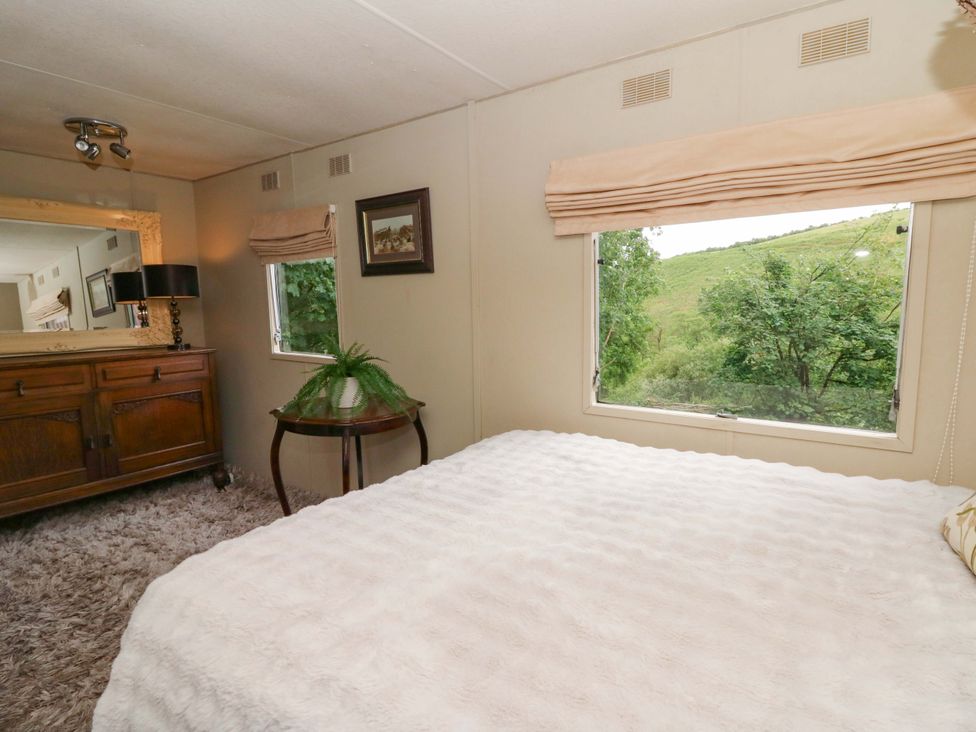 A bedroom with a bed and dresser at Gwybedog in Llanwrda