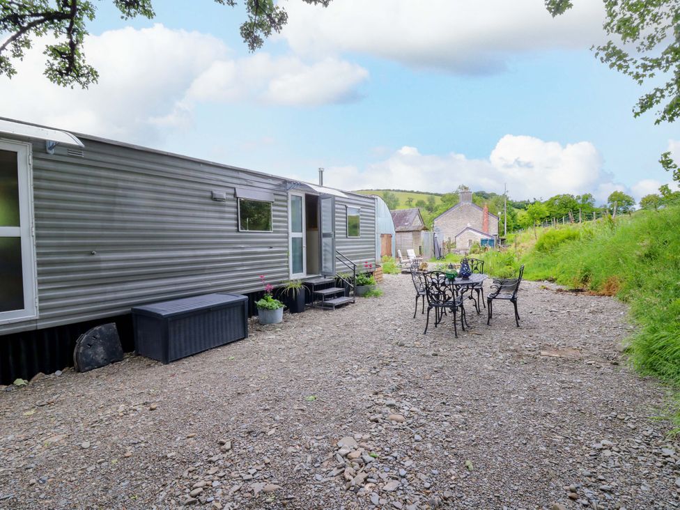 An outdoor seating area with a trailer and a table at Gwybedog in Llanwrda