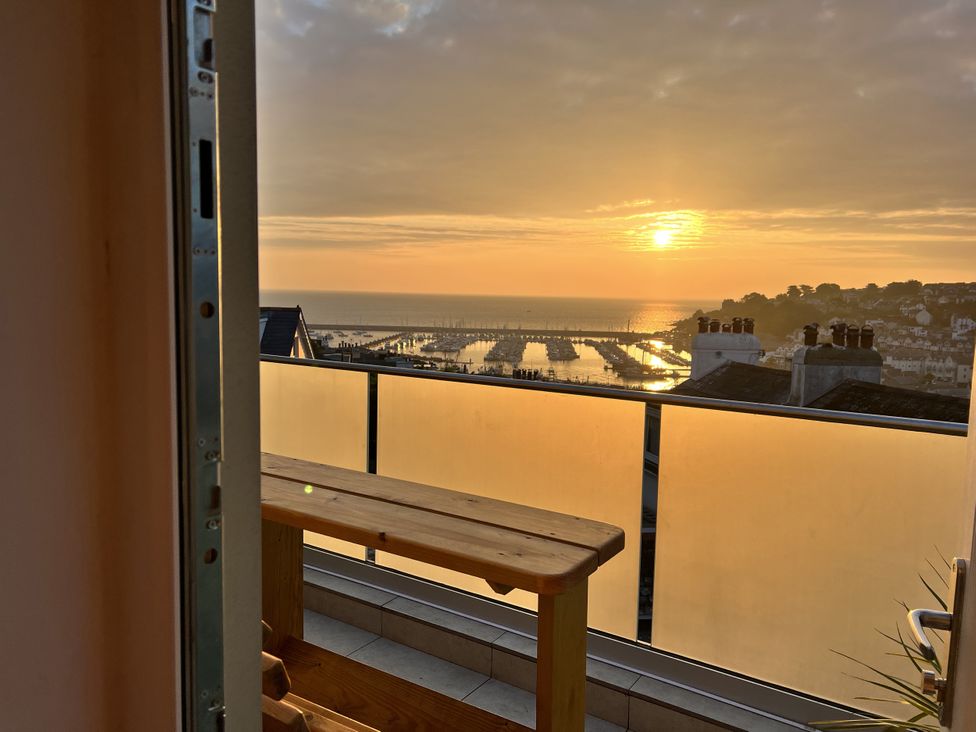 A balcony with a wooden bench overlooking a marina at Still Waters in Brixham