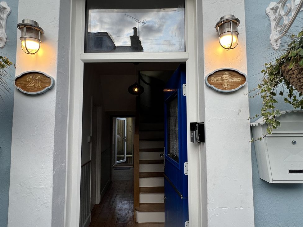 A hallway with a staircase and blue front door at Still Waters in Brixham