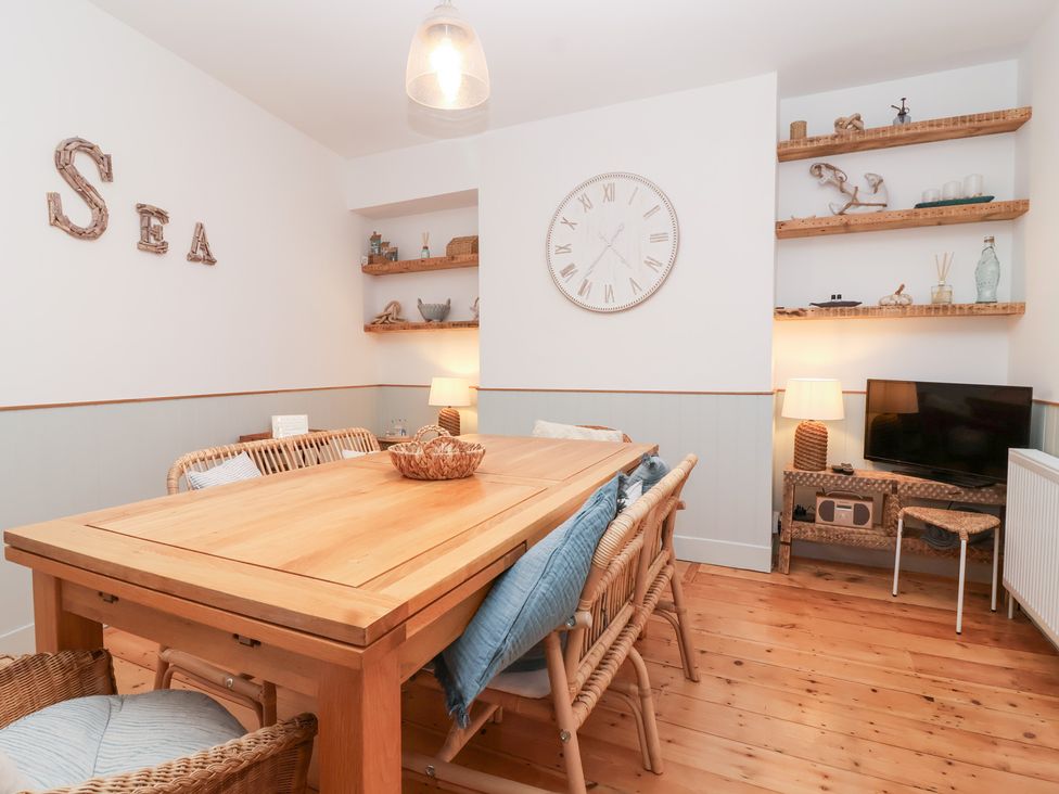 A dining room with a wooden table and chairs at Still Waters in Brixham