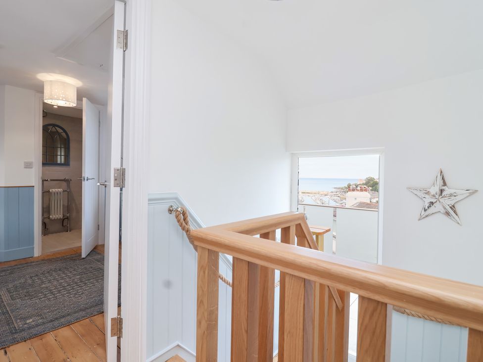 A hallway with a stair railing and a window at Still Waters in Brixham